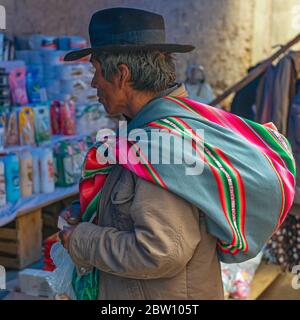 Ritratto di un uomo indigeno Boliviano Tarabuco con il suo tessuto colorato utilizzato come borsa sul mercato locale vicino a Sucre City, Bolivia. Foto Stock