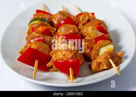 carne di pollo cruda marinata su spiedini di legno, maiale, pollo, manzo in piatto bianco su sfondo bianco. Foto Stock