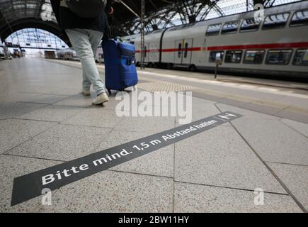 Lipsia, Germania. 27 maggio 2020. Un viaggiatore cammina dietro un pennarello con istruzioni sulla distanza attraverso un binario alla stazione centrale di Lipsia. Con più dispenser per mani disinfettanti, più frequenti pulizie e luce anti-virus, Deutsche Bahn vuole prepararsi alle stazioni per il crescente traffico di passeggeri nella crisi della corona. Con le nuove macchine per la pulizia, le superfici potrebbero essere disinfettate più estesamente che in passato. Credit: Jan Woitas/dpa-Zentralbild/dpa/Alamy Live News Foto Stock