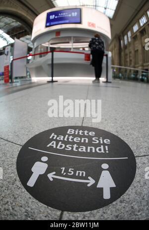 Lipsia, Germania. 27 maggio 2020. Un viaggiatore si trova dietro un pennarello con istruzioni sulla distanza alla stazione centrale di Lipsia. Con più dispenser per mani disinfettanti, più frequenti pulizie e luce anti-virus, Deutsche Bahn vuole prepararsi alle stazioni per il crescente traffico di passeggeri nella crisi della corona. Con le nuove macchine per la pulizia, le superfici potrebbero essere disinfettate più estesamente che in passato. Credit: Jan Woitas/dpa-Zentralbild/dpa/Alamy Live News Foto Stock