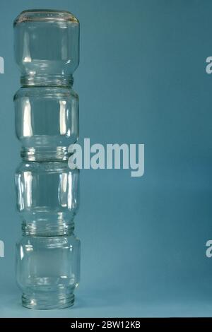 Fila verticale di vetro quattro vasi a sinistra su sfondo blu, cornice verticale. Foto Stock