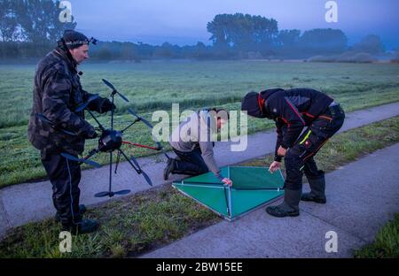 27 maggio 2020, Meclemburgo-Pomerania occidentale, Dummerstorf: Gli attivisti del benessere animale stanno preparando un drone con una termocamera per il decollo prima dell'alba accanto a un prato. I soccorritori di animali usano l'aereo per cercare piccoli fiabe che giacciono nell'erba. Gli animali sono trovati da attivisti del benessere animale con l'aiuto di una termocamera su un drone e prima dell'alba sono circondati e protetti da una sorta di castello sulla spiaggia. Si stima che ogni anno nel solo nord-est, circa 26,000 falci vengono uccisi durante le operazioni di falciatura. Con i droni, i membri dell'animale selvaggio ai Foto Stock