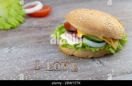 preparare panini per la colazione. hamburger delizioso su una superficie di legno cosparsa di semi di sesamo. Foto Stock