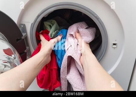 lavatrice bianca a caricamento frontale, piena di vestiti. lavanderia per la pulizia. lavanderia sporca nella lavatrice. Foto Stock
