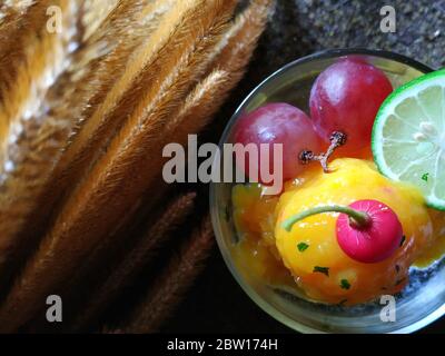 Sorbetto al mango fatto in casa in un bicchiere con pompelmo, lime e ciliegia locale. Foto Stock