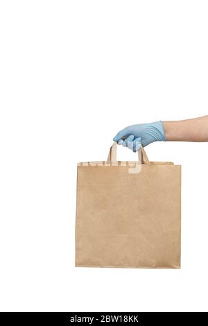 Uomo di consegna in guanti medici che tengono borsa di carta artigianale con cibo. Consegna di cibo di coronavirus. Il volontario porta una scatola di cibo. Donazione, quarantena conc Foto Stock