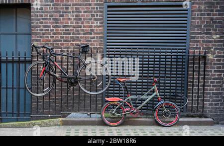 Biciclette incatenate su ringhiere metalliche contro un muro di mattoni. Londra Foto Stock