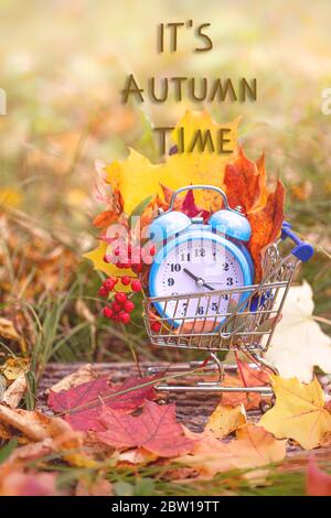 Orologio d'epoca e foglie d'acero nella foresta d'autunno. Stile immagine stagione autunno. Concetto di ora legale di ritorno. Ora legale. Foto Stock