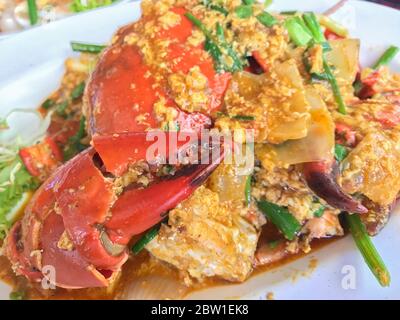 Granchio in polvere di curry fritto in padella su un tavolo di legno, colpo di primo piano, Foto Stock