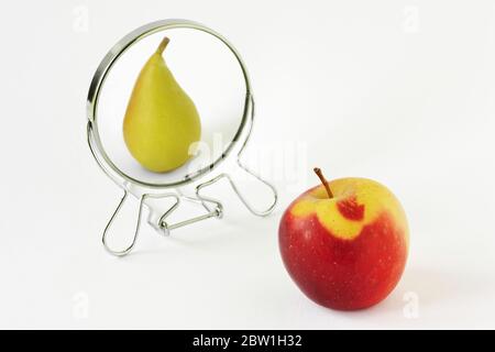 Mela rossa guardando nello specchio e vedendosi come una pera - concetto di dismorfobia e immagine distorta di sé Foto Stock