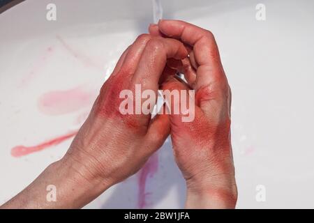 primo piano di mani femminili coperte di sangue che vengono lavate in un lavello, concetto di omicidio, violenza, operatore sanitario Foto Stock