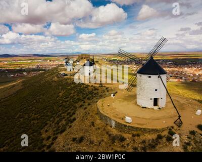 Vista aerea del bianco torri cilindriche e appuntite di tetti di vecchi mulini a vento spagnolo sullo sfondo con Consuegra cityscape Foto Stock