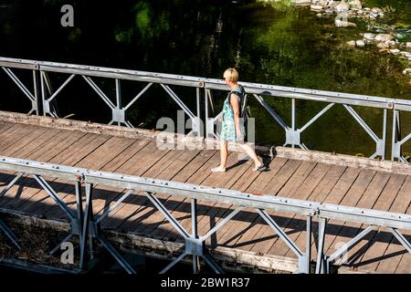 Donna che attraversa il ponte sul fiume Lowther, vicino a Askham, Cumbria Foto Stock