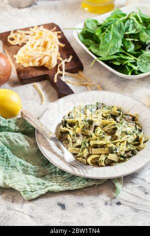 Tagliatelle con spinaci e funghi su un piatto. Cibo vegetariano Foto Stock