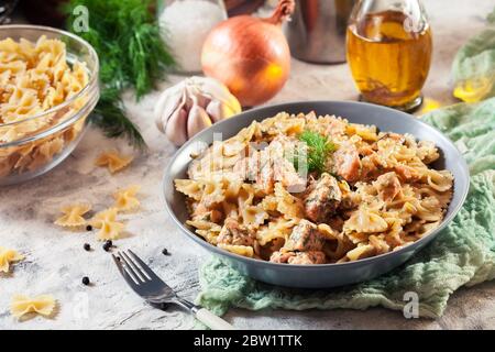 Pasta di farfalle cremosa con salmone, parmigiano e aneto. Piatto italiano Foto Stock