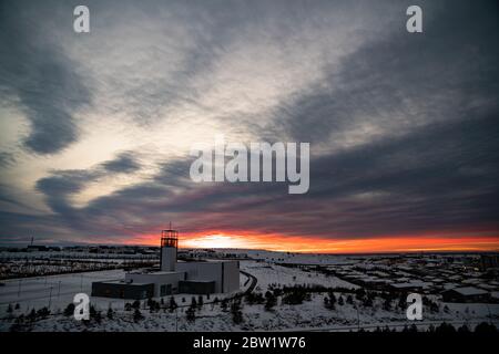 Bellissimo tramonto con le nuvole drammatiche dietro una chiesa nella neve Foto Stock