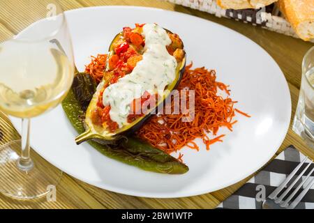 Piatto colorato di melanzane a metà cotte con ripieno di verdure assortite servite con salsa di yogurt tzatziki Foto Stock