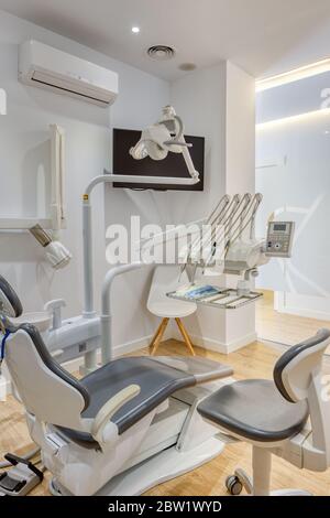 Moderna cassetta per ambulatori dentali completamente attrezzata, con pareti bianche e pavimento in legno. Radiografia dentale visualizzata sul monitor. Foto Stock