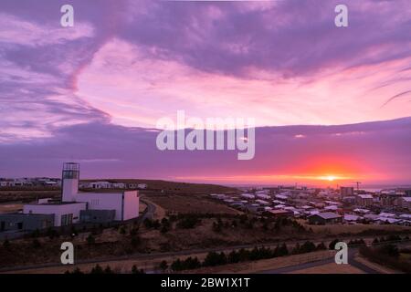 Splendido tramonto magenta su una piccola città con le sue nuvole spettacolari e una chiesa in primo piano Foto Stock