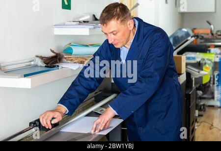 La stampa operatore taglia carta su una macchina trinciatrice Foto Stock