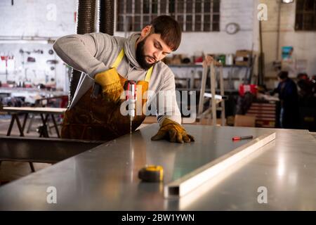 Punta su giovani operai di metallo che perforano fori in strutture in acciaio con trapano elettrico senza fili Foto Stock