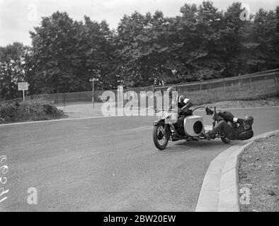 I motociclisti hanno fatto pratica finale sul circuito di Crystal Palace Road Racing per la riunione del Gran Premio di Londra di oggi (sabato). Qui il passeggero sta eseguendo un acrobatico per mantenere l'equilibrio come B. H. Kimberly (Norton) intorno alla curva in pista. 17 luglio 1937. Foto Stock