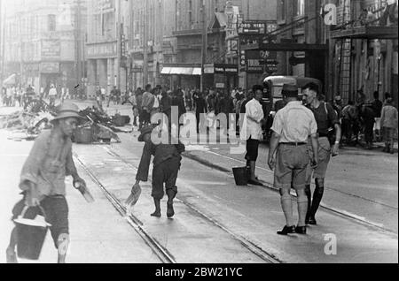 Una squadra di riabilitazione si ripulisce nella Nanking Road, Shanghai, dopo un raid aereo. Un debriefing pilota in background. Dopo ogni raid, le strade sono piene di detriti e vittime umane dei legami. 10 settembre 1937 Foto Stock