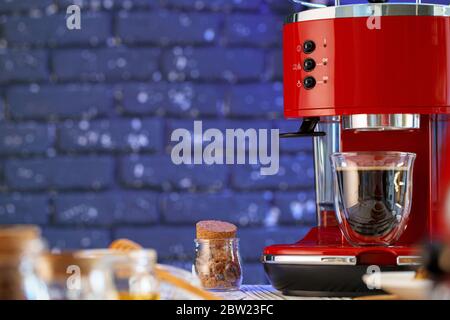 Macchina da caffè rossa con un bicchiere sul banco da cucina Foto Stock