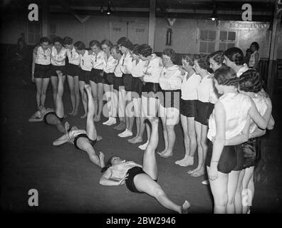 Le ragazze ferroviarie trovano un modo permanente per la salute. I lavoratori della Great Western Railway che guardano tre dei loro compagni eseguono uno degli esercizi della classe 'Keep Fit'. Cento ragazze frequentano regolarmente le lezioni allo Stanley Street Institute di Paddington London. 2 dicembre 1937 Foto Stock