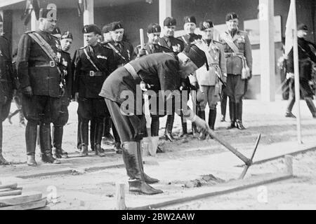 Mussolini si mette al suo punto con un picchietto. Il signore Mussolini, con una pickax, ha inaugurato ufficialmente i lavori di scavo del nuovo edificio della "Casa della Littoria" a Roma. L'edificio fa parte dello schema di miglioramento per il XVI anno dell'era fascista, la cui apertura ha appena celebrato. 1 novembre 1937 Foto Stock