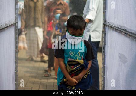 Bekasi, Giava Occidentale, Indonesia. 29 maggio 2020. Un ragazzo che indossa una maschera facciale attraverso la camera disinfettante prima di entrare nella moschea di al-Barkah, Bekasi, Giava Occidentale. Per incontrare la nuova domanda normale per la prima volta Venerdì preghiere in Congregazione, che si tiene oggi, Venerdì 29 maggio, l'attuazione della preghiera in Congregazione rimane il protocollo sanitario prevenzione del virus di Corona diffusione credito: Muhammad Zaenuddin / ZUMA Wire / Alamy Live News Foto Stock