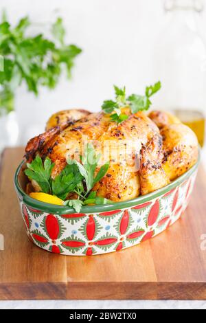Pollo arrosto intero con prezzemolo fresco e spicchi di limone in un piatto di festa Foto Stock