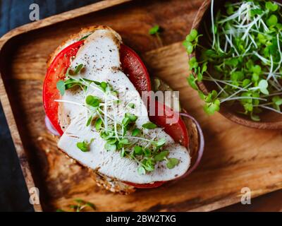 Vista dall'alto del panino aperto con carne di tacchino a fette e verdure fresche in un vassoio di legno concetto di alimentazione sana. Foto Stock