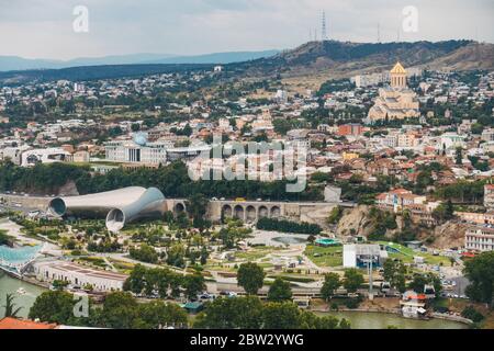 Guardando fuori sulla città di Tbilisi, Georgia dal Giardino Botanico sulla collina. La struttura cilindrica in metallo è il Teatro musicale Tbilisi Foto Stock