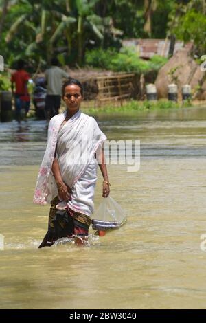 Nagaon, Assam / India - 29 2020 maggio: UNA donna con verdure sulla sua mano che guastano la strada allagata a Tetelisara villaggio colpito alluvione vicino Kampur nel distretto di Nagaon di Assam il venerdì. Credit: Dita TALUKDAR/Alamy Live News Foto Stock