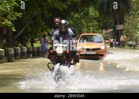 Nagaon, Assam / India - 29 2020 maggio: La gente sulle loro automobili e biciclette che attraversano la strada allagata a Tetelisara villaggio colpito alluvione vicino a Kampur nel distretto di Nagaon di Assam venerdì. Credit: Dita TALUKDAR/Alamy Live News Foto Stock