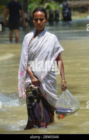 Nagaon, Assam / India - 29 2020 maggio: UNA donna con verdure sulla sua mano che guastano la strada allagata a Tetelisara villaggio colpito alluvione vicino Kampur nel distretto di Nagaon di Assam il venerdì. Credit: Dita TALUKDAR/Alamy Live News Foto Stock