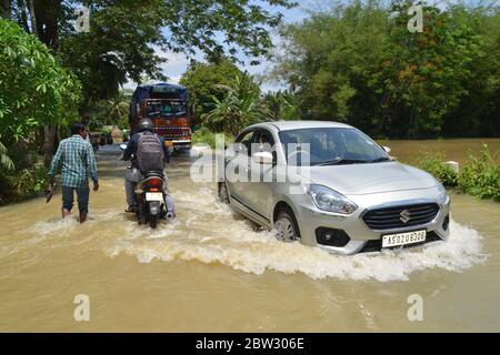 Nagaon, Assam / India - 29 2020 maggio: La gente sulle loro automobili e biciclette che attraversano la strada allagata a Tetelisara villaggio colpito alluvione vicino a Kampur nel distretto di Nagaon di Assam venerdì. Credit: Dita TALUKDAR/Alamy Live News Foto Stock