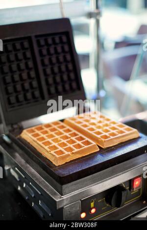 Waffle appena sfornati in una macchina per waffle professionale Foto Stock
