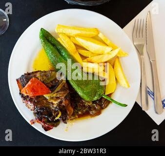 Gustose guance di maiale stufate con sugo di verdure, patate fritte e pepe verde al forno Foto Stock