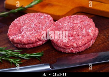 Tagli di carne grezza per hamburger su superficie di legno Foto Stock