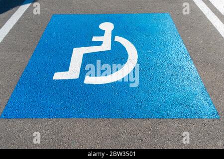 Parcheggio con simbolo dipinto per disabili su asfalto, posti auto per disabili. Spazio di parcheggio vuoto per disabili Foto Stock