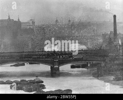 Vista a fuoco lungo del fiume Tamigi che mostra le torrette della Torre di Londra e Tower Hill e chiatte ormeggiate sul fiume. 3 maggio 1933 Foto Stock