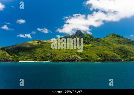 Isola tropicale con montagne rocciose sulla cima. Acque blu intenso di fronte all'isola tropicale. Isole Yasawa Foto Stock