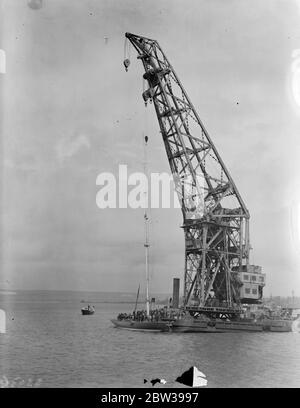 Il palo della fatica al Royal Dockyard a Portsmouth . Il compito di steppare l'enorme albero in acciaio dello yacht Endeavour , che è stato appena lanciato a Gosport , è stato completato con l'assistenza di una grande gru al Royal Dockyard a Portsmouth . Lo yacht del signor ' Tommy' Sopwith' si impegnerà per la Coppa America in settembre. Foto mostra ; la gru che abbassa l'enorme albero di acciaio in posizione nel Royal Dockyard a Portsmouth . 19 aprile 1934 30s, 30s, 30s, 30s, 30s, trents, 19the30 Foto Stock