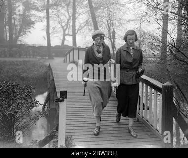 Signore parlamentare golf a Ranelagh . Il club di golf Ladies Parliament ha aperto la sua riunione di primavera al ranelagh Club di Londra . Spettacoli fotografici ; due golfisti lady fanno la strada più sopra il ponte sulla loro strada per il campo da golf . 27 aprile 1934 Foto Stock