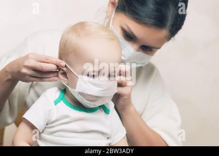 mamma mette su una maschera medica viso alla sua figlia piccola, primo piano Foto Stock
