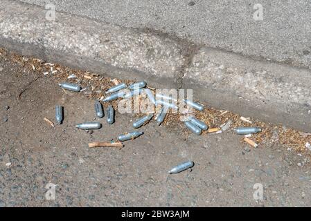 Pila di contenitori vuoti di protossido di azoto scartati sul roadside.Normally usato da industria di ristorazione per panna montata, anche usato come una droga ricreativa Foto Stock