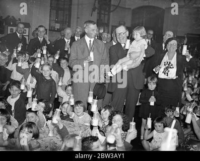 Sig. Walter Elliot Ministro dell' agricoltura beve latte con bambini in una scuola londinese. Il signor Elliot e il signor Astor sono i 1° ottobre 1934 Foto Stock