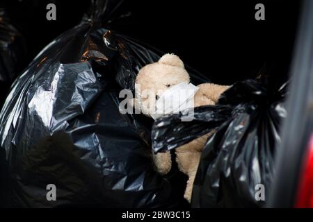 un orsacchiotto con un bendaggio medico sul viso giace sui sacchetti di spreco Foto Stock